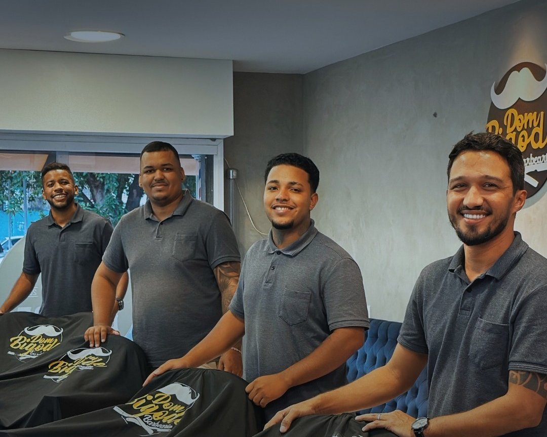 A equipe da Dom Bigode, de polo cinza, posando atrás das cadeiras cobertas com as capas da casa