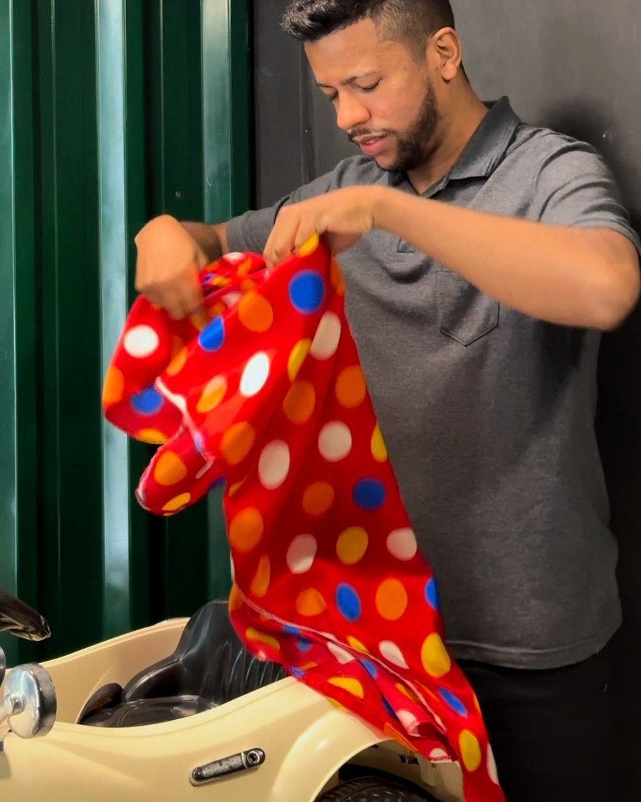 Barbeiro preparando a capa de bolinhas ao lado da cadeira em forma de carrinho